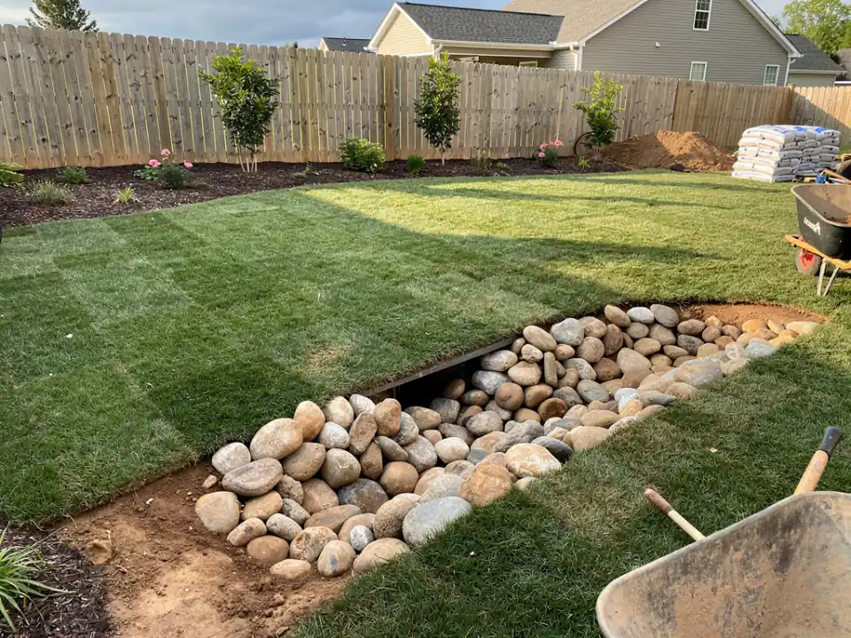 River-rock drain outlet at the edge of a restored lawn.