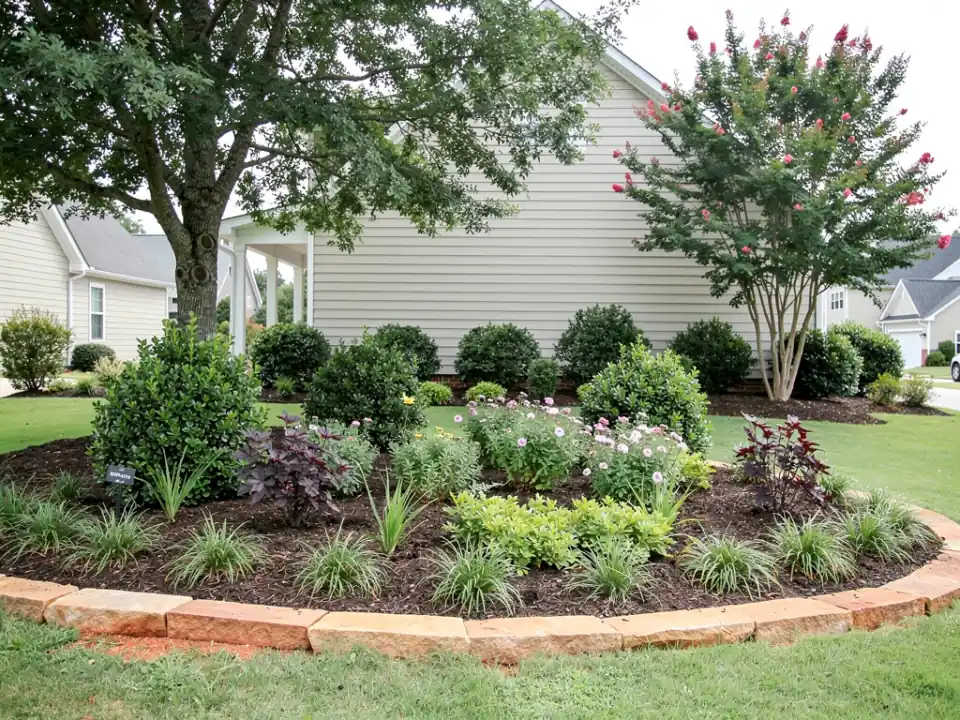 New layered planting beds with a curved edge in front of a home